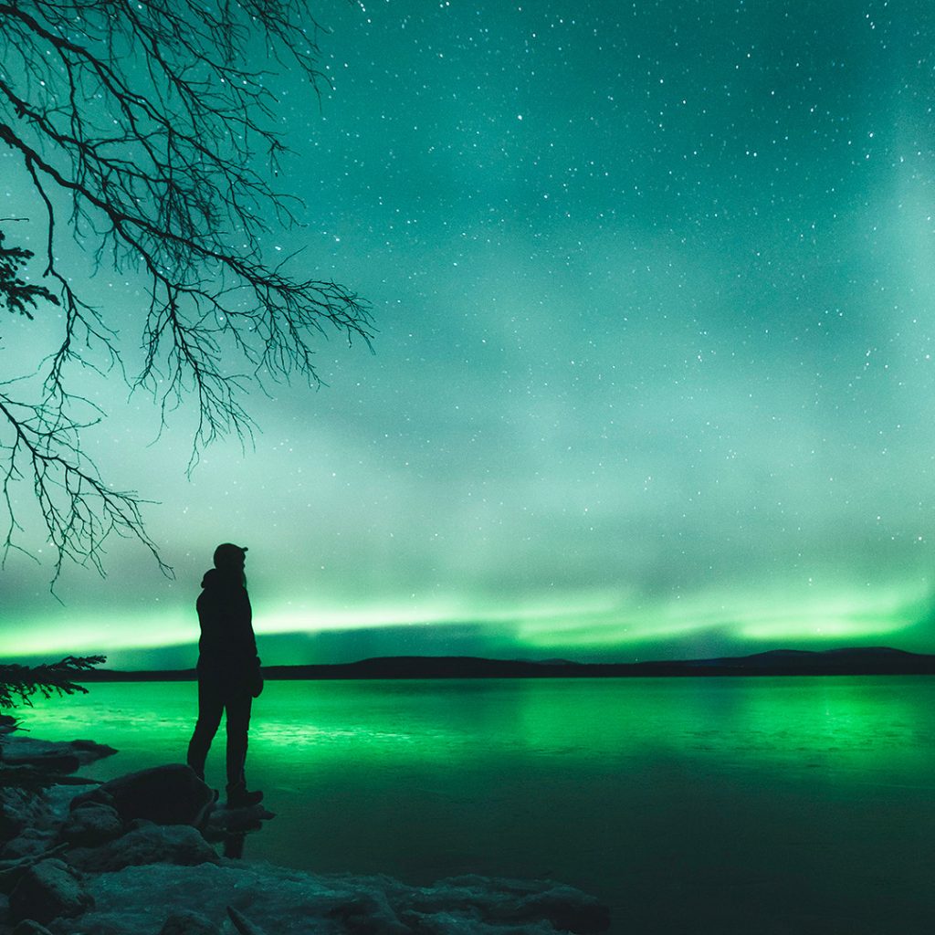 Northern lights reflecting from the surface of the lake. | Lapland Luxury