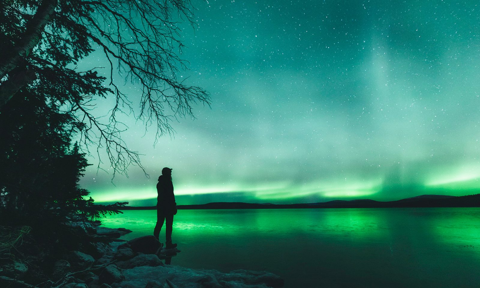 Northern lights reflecting from the surface of the lake. | Lapland Luxury