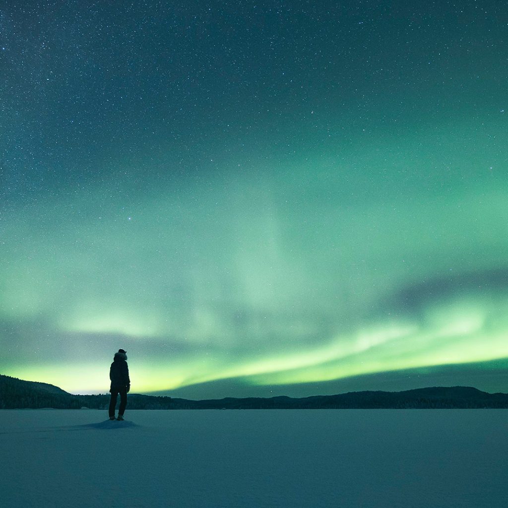 Man enjoying northern lights in Lapland. Lapland Luxury