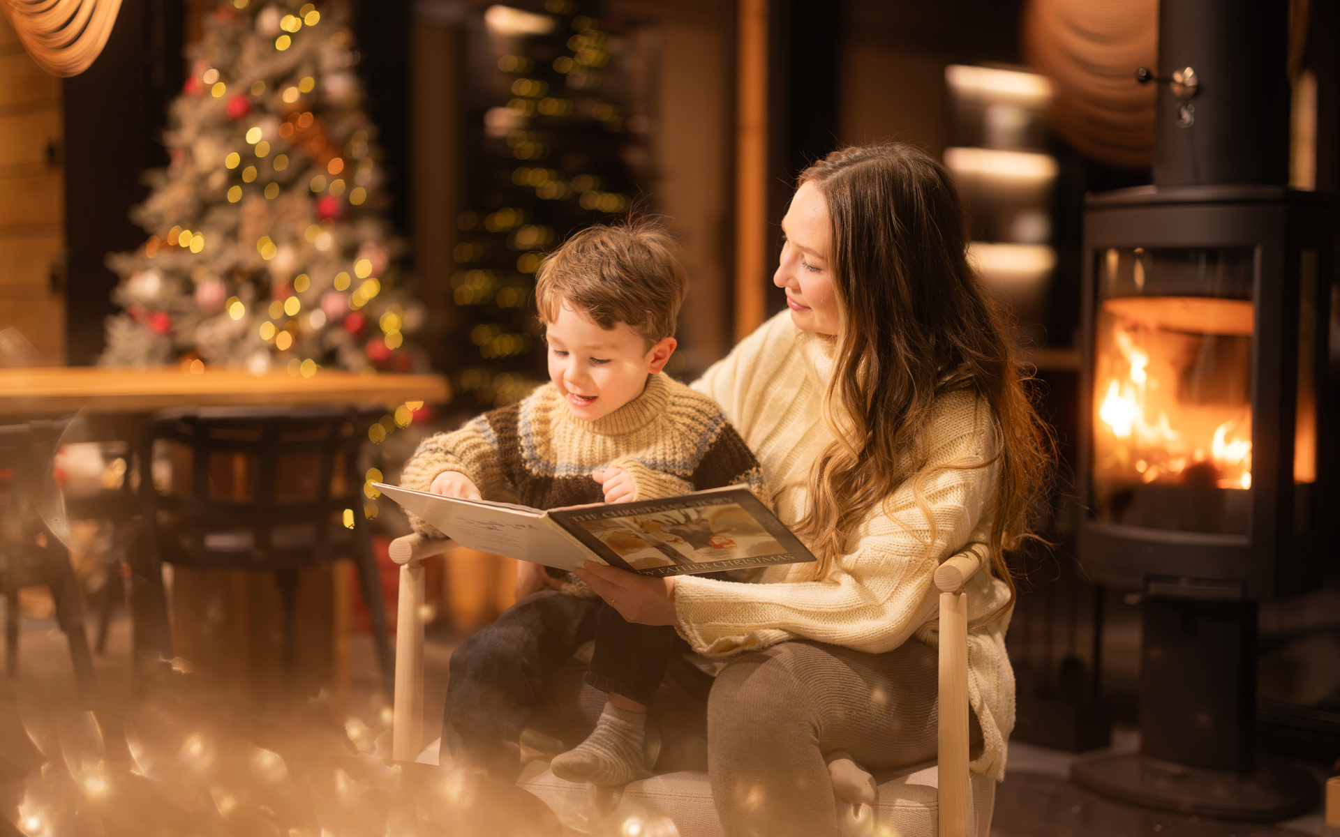 Mom reading a storybook to a little boy during Christmas. Lapland Luxury.