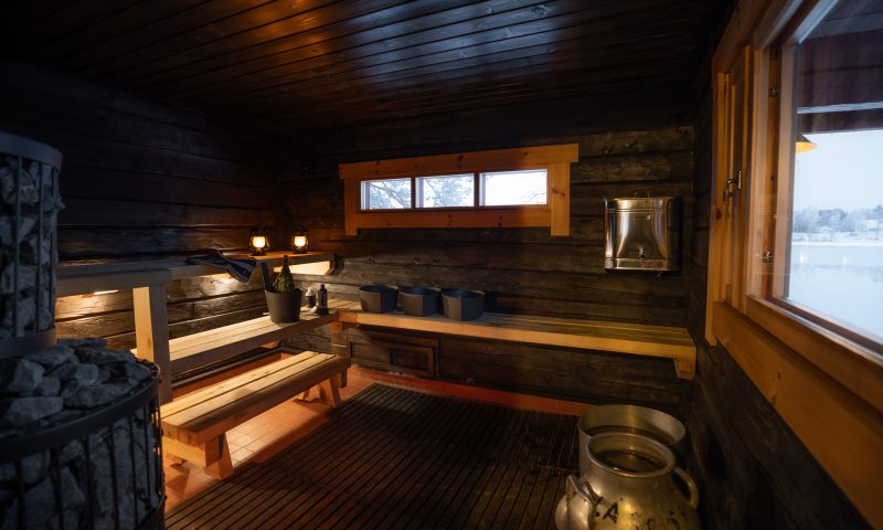 Traditional Finnish sauna on the riverbank of the private island. Lapland Luxury.